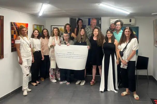 Fotografía de grupo de las participantes en Am Israel Jai, sosteniendo un texto de la exposición ante las obras.