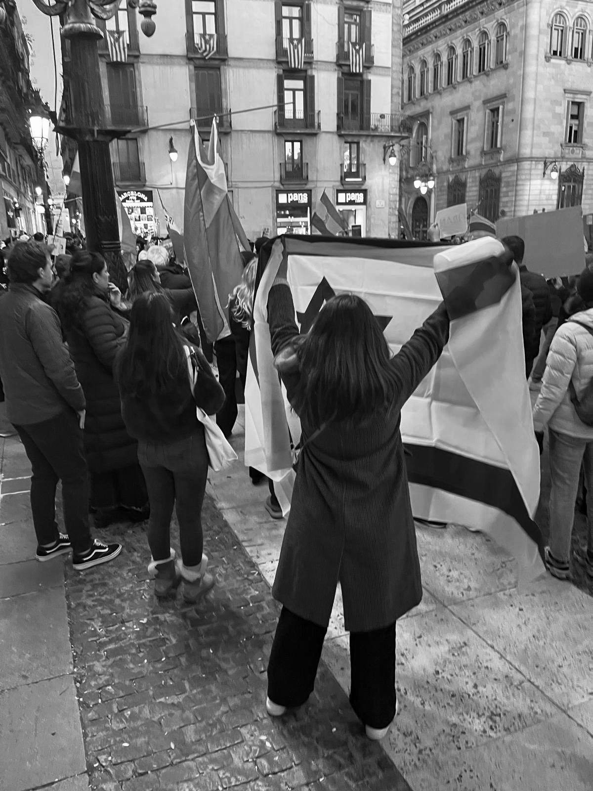 Una persona despliega una pancarta en una plaza durante una concentración.