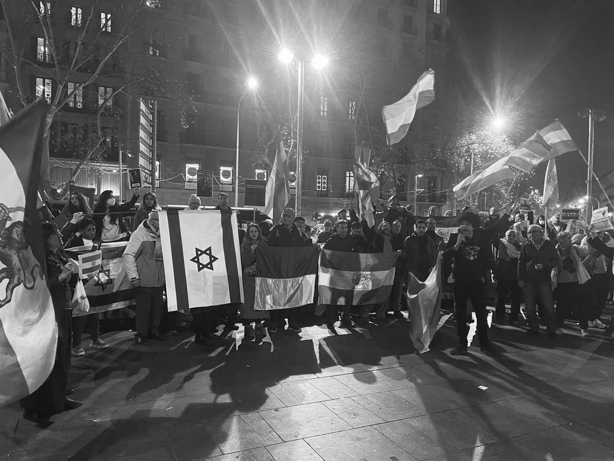 Concentración nocturna con banderas en una calle de Barcelona.